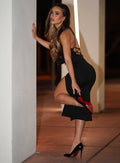 left side  profile view of a model wearing our black dress with a  high side slit  on the side and a criss cross adjustable back straps