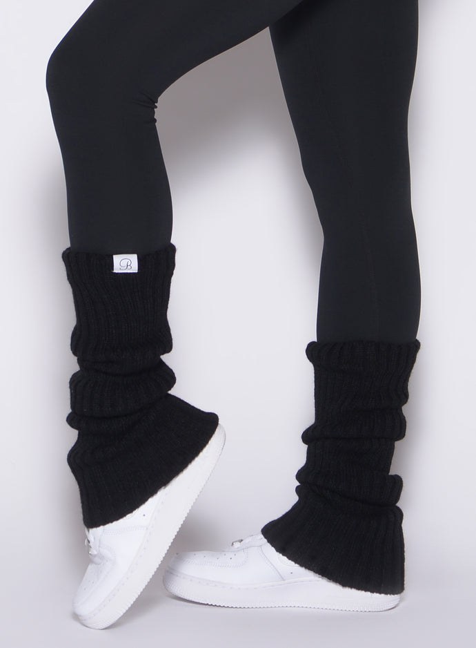 left side close up view of a model wearing the Luxe Leg Warmers in black color