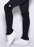 left side view of a model wearing the Luxe Leg Warmers in black color