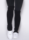 front profile view of a model wearing the Luxe Leg Warmers in black color paired with the matching leggings