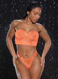 front profile view of a model in indoors with water droplets falling around her wearing the Neon Nights Bikini Bandeau in Mango Blaze color