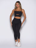 front view of a model with both hands resting on her thighs wearing the Movement 7/8 Leggings in heathered black color