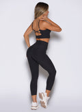 right side profile view of a model wearing the Movement 7/8 Leggings in heathered black color