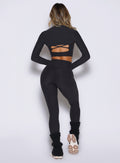 back side view of a model wearing the Movement 7/8 Leggings in heathered black color paired with the matching tops 