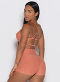 back left side profile view of a model looking over her shoulder wearing the MulTie Sports Bra in spiced maple color