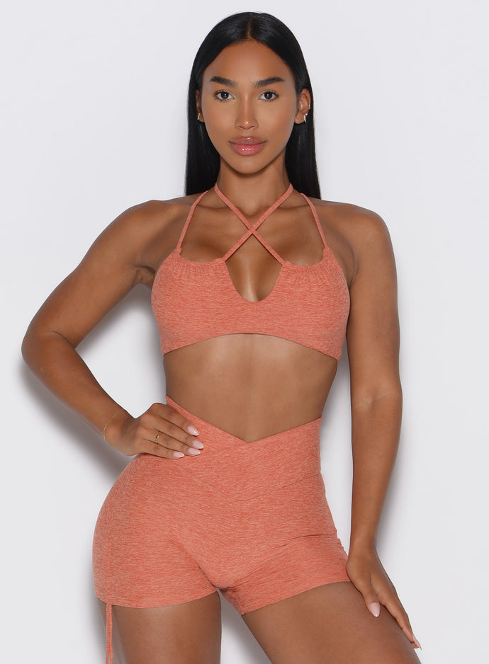 Woman wearing a orange sports bra and shorts set on a white background