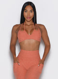 Woman wearing a orange sports bra and leggings set on a white background