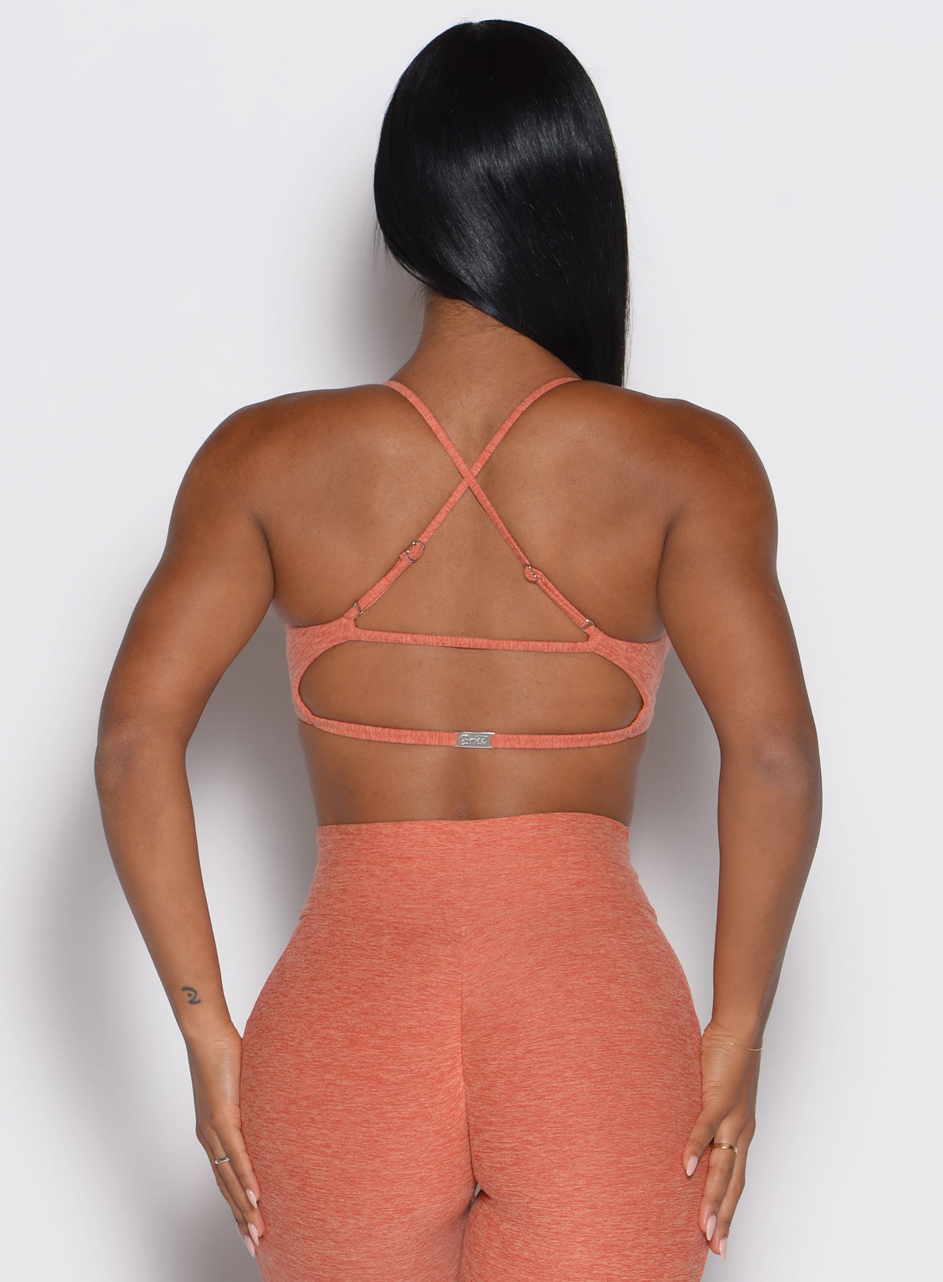 back view of a model showcasing the multi-way tie straps on the MulTie Sports Bra in spiced maple color