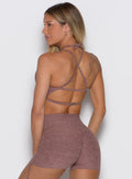 back profile view of a model facing to the left side wearing the MulTie Sports Bra in walnut color 