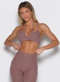 Woman wearing a brown sports bra and leggings on a light gray background