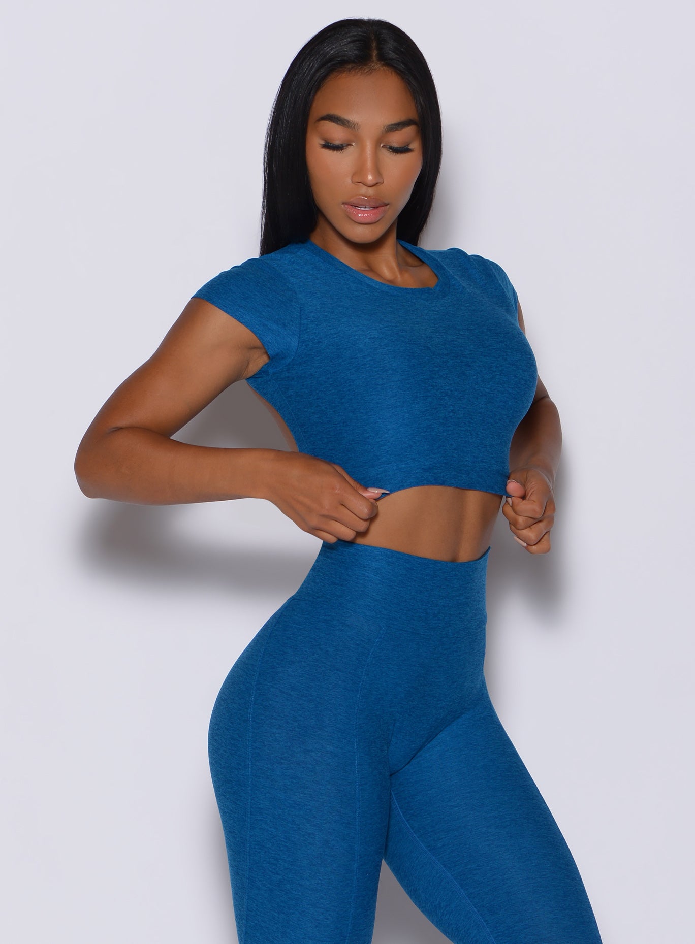Front profile view of a beautiful model flaunting our open back tee in azure color along with a matching leggings