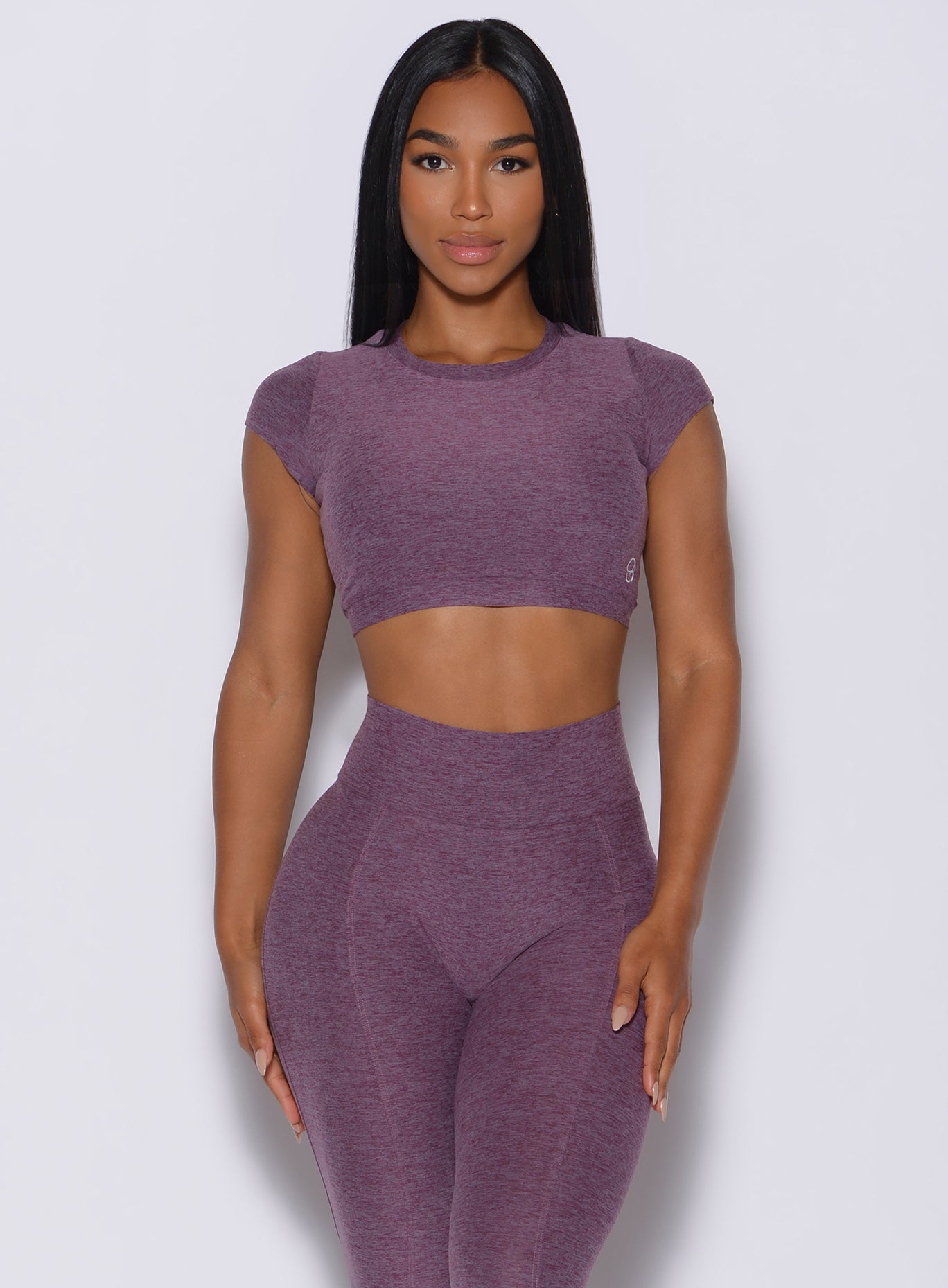 Front profile view of a model in our open back tee in Regal Purple color and a matching high waist leggings