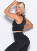 left side view of a model facing to her left wearing Muscle Scrunch Tank in Black color
