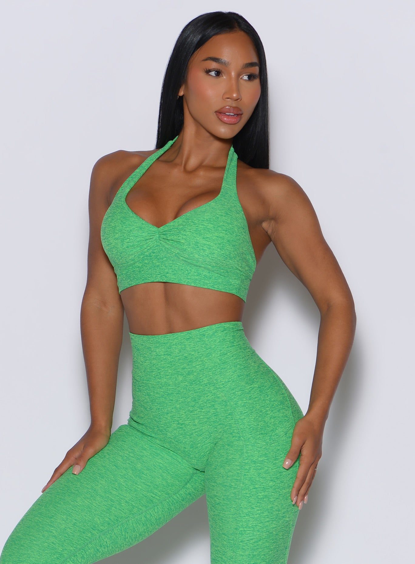 Front profile view of a model facing to her left wearing our backless bra in Neon Miami Beach color along with the matching leggings