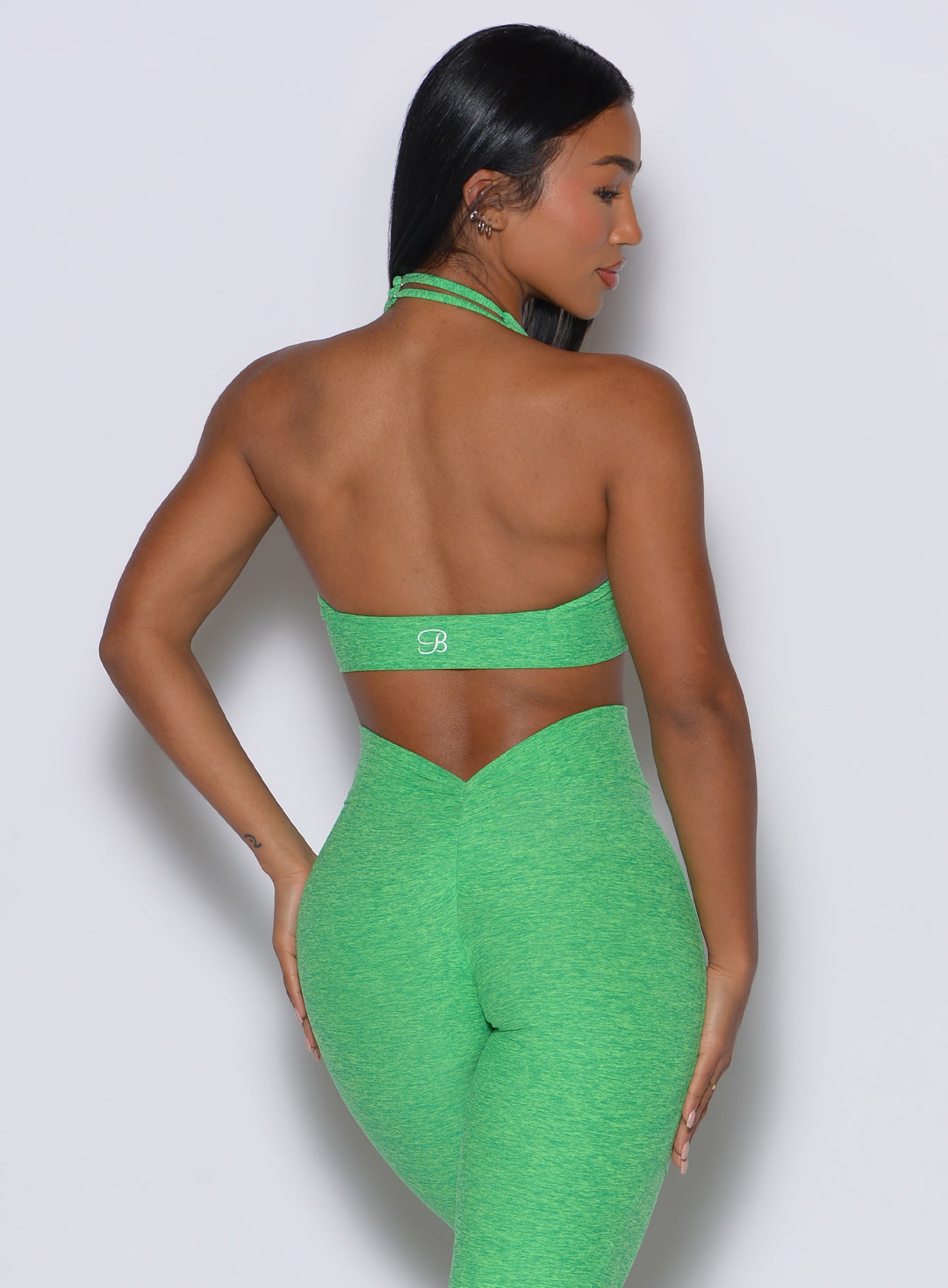 Back profile view of a model facing to her right  wearing our backless bra in Neon Miami Beach color along with the matching leggings