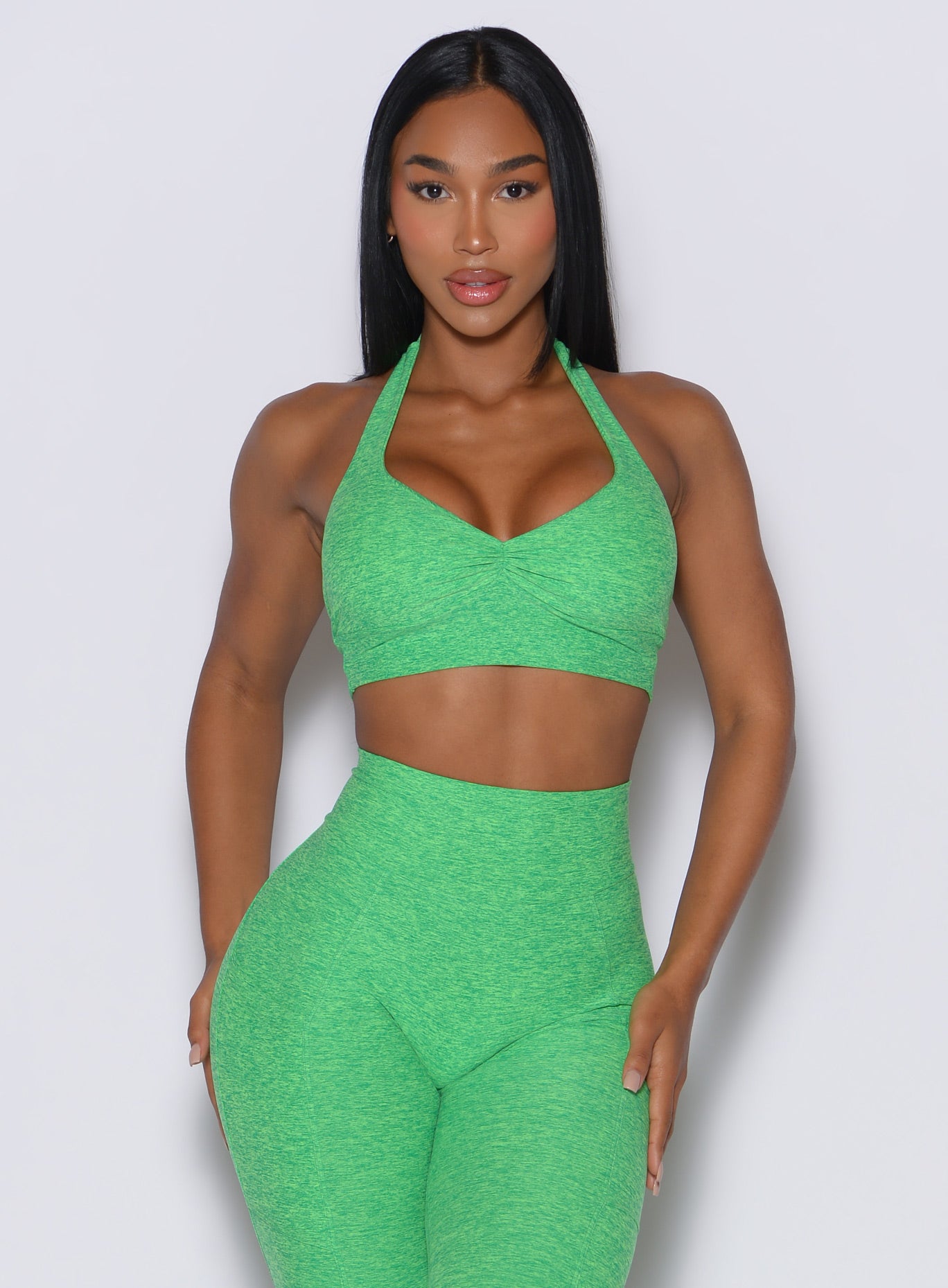 front profile view of a model wearing our backless bra in Neon Miami Beach color along with the matching leggings 