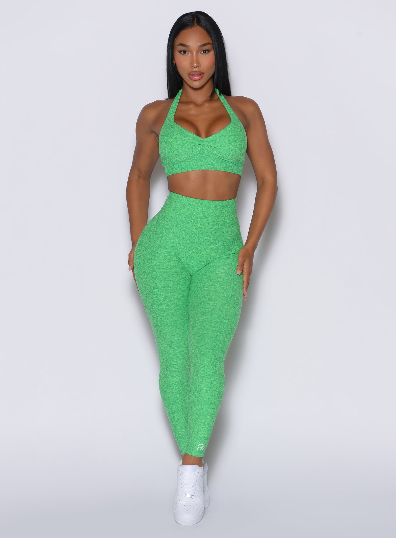 front profile view of a model wearing our V back leggings in Neon Miami Beach color along with a matching bra