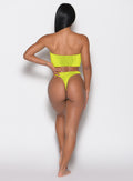 back profile view of a model with her right hand on her waist wearing the Neon Nights Bikini Bottoms in Lemon Drop color 