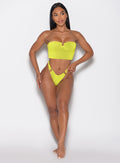 front profile view of a model with her left hand on the band wearing the Neon Nights Bikini Bottoms in Lemon Drop color 