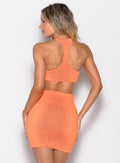 back profile view of a model facing to the left side wearing the Neon Nights Bikini Top in Mango Blaze color 