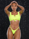 Model facing forward wearing our Tropical Tease Bikini Top in Neon Yellow color and the matching Tropical Tease Bikini Bottoms with water droplets falling all around her
