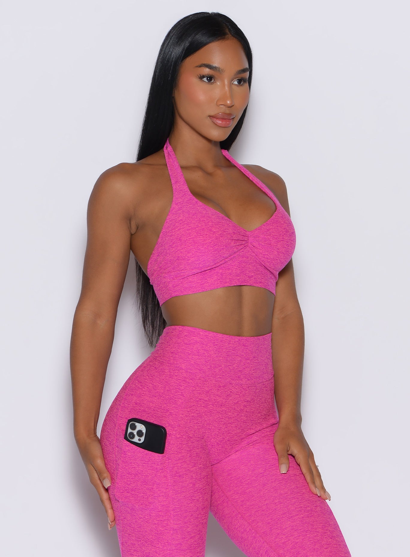 right side profile view of a model wearing our backless bra in Neon Pink Sorbet color along with the matching high waist leggings