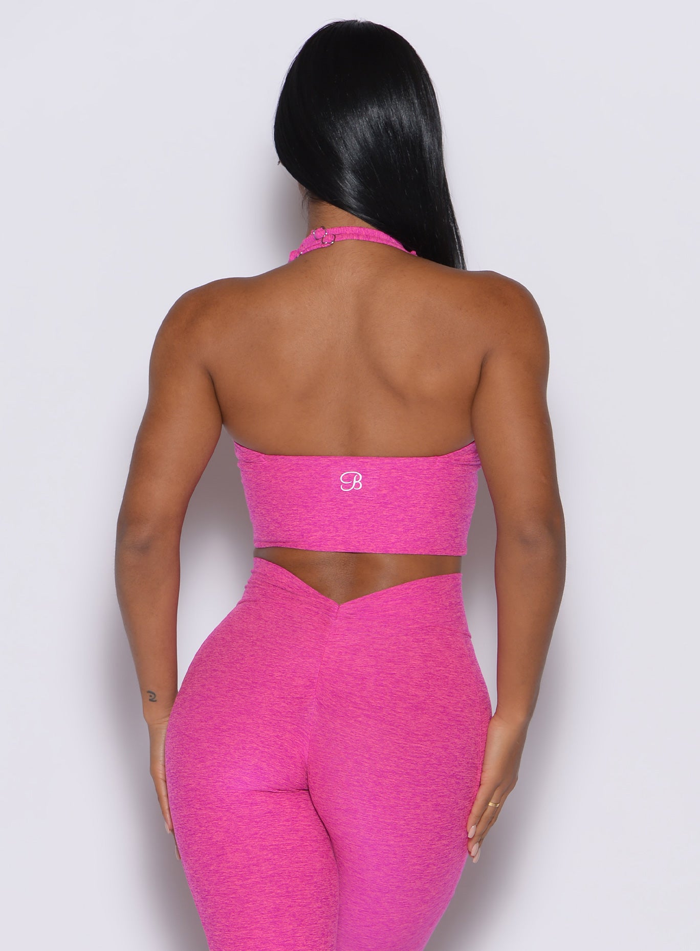 back profile picture of a model wearing our longline backless bra in Neon pink sorbet color along with a matching leggings