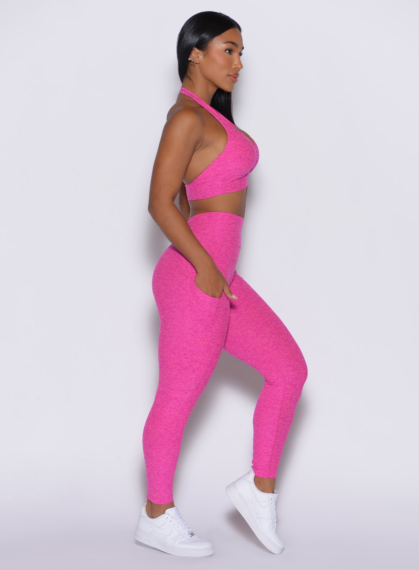 right side profile picture of a model wearing our V back leggings in Neon pink sorbet color along with a matching bra