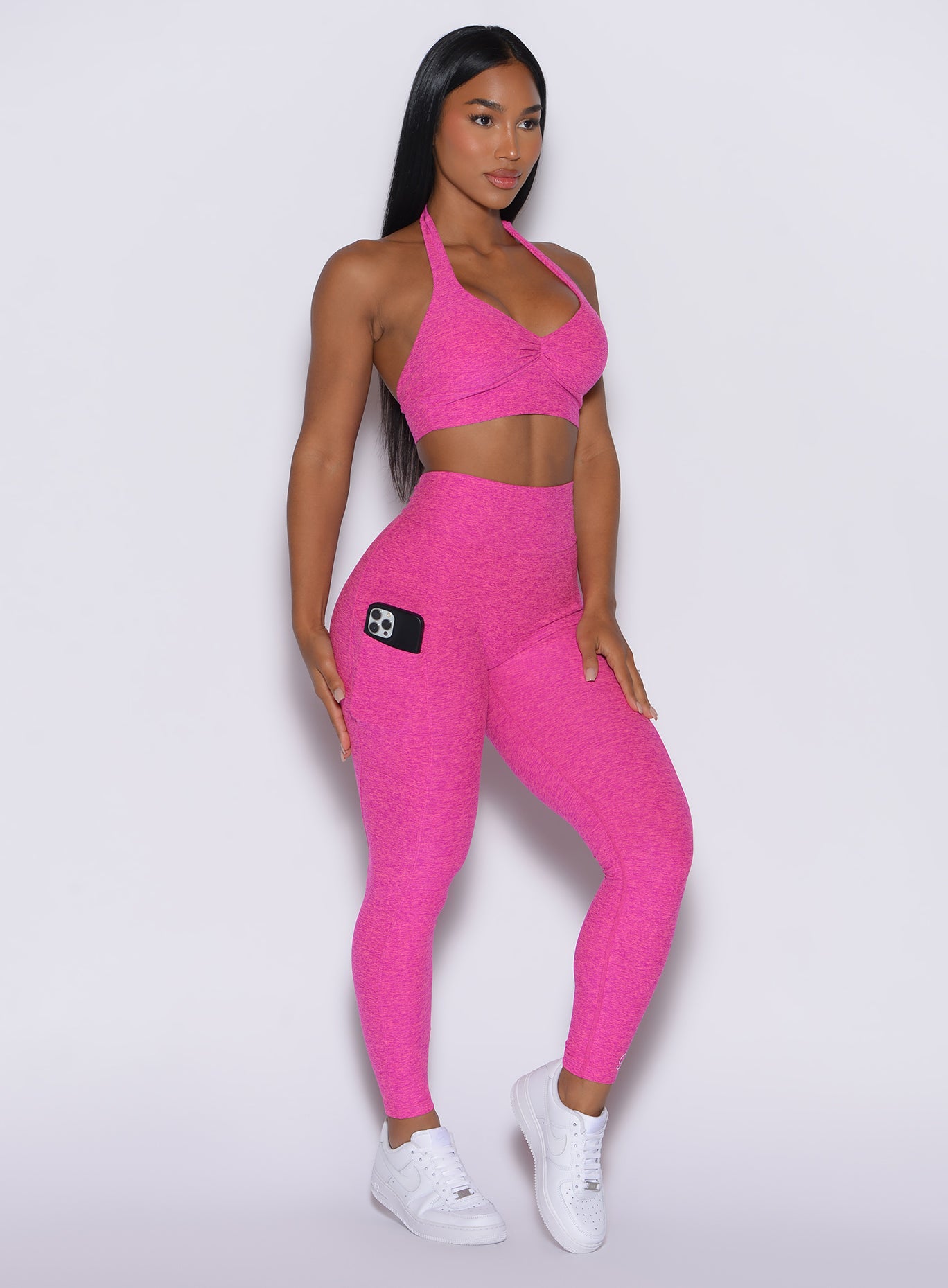 front profile view of a model wearing our V back leggings in Neon pink sorbet color along with a matching sports bra