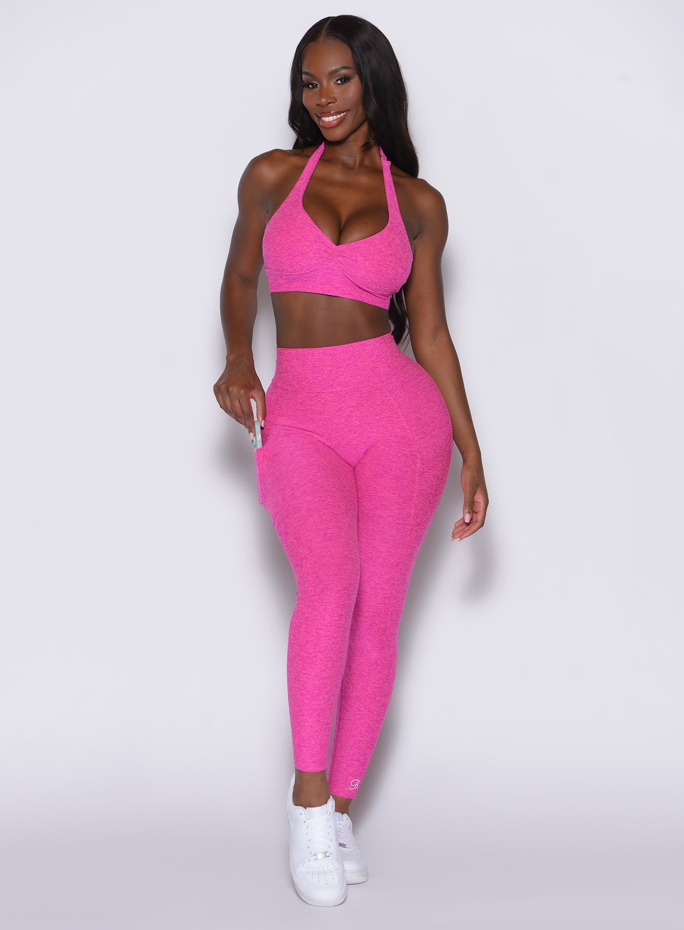 front profile view of a model wearing our V back leggings in Neon pink sorbet color along with a matching bra