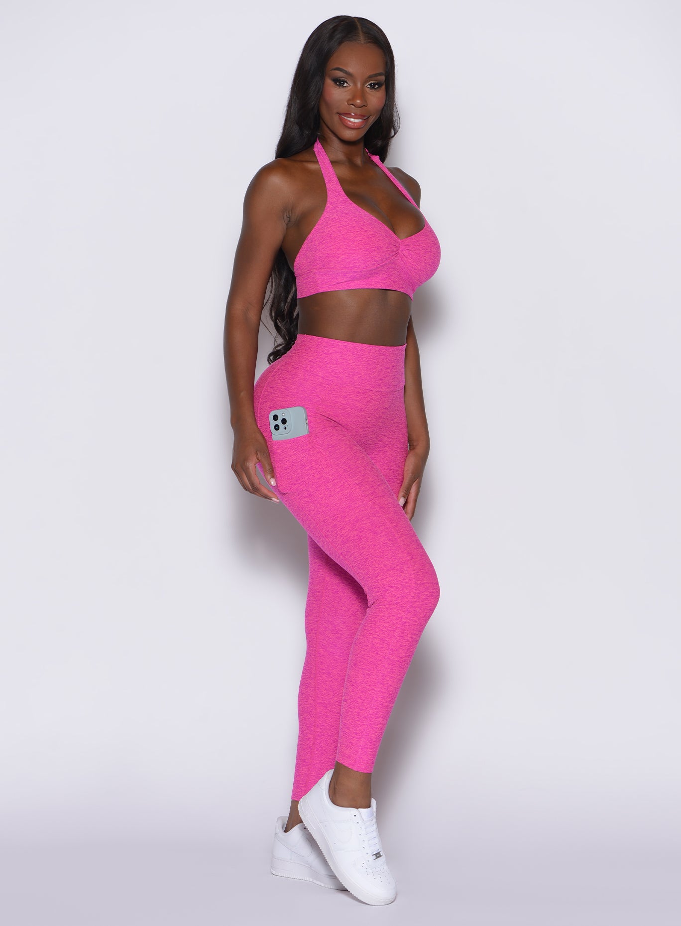 left side profile view of a model angled right wearing our V back leggings in Neon pink sorbet color along with a matching bra