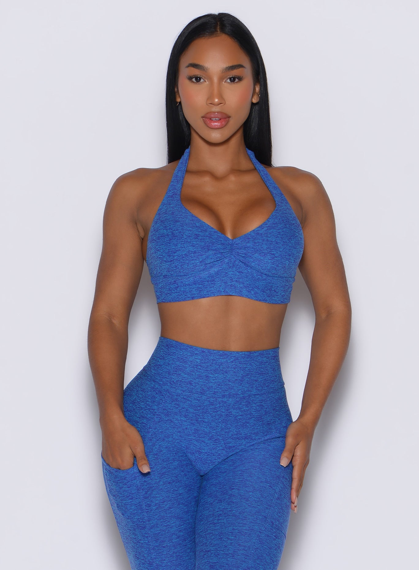 front profile picture of a model wearing our backless bra in Neon blue rave color along with the matching leggings