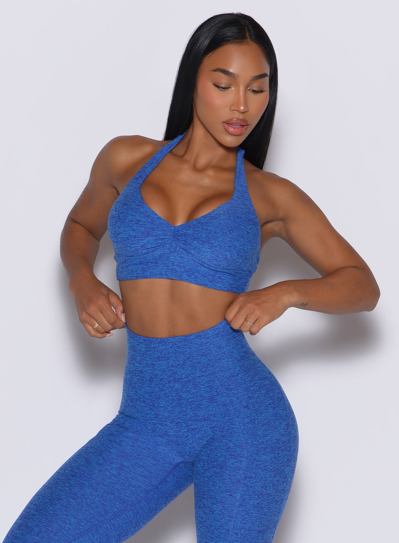 front profile view of a model wearing our backless bra in Neon blue rave color along with the matching leggings