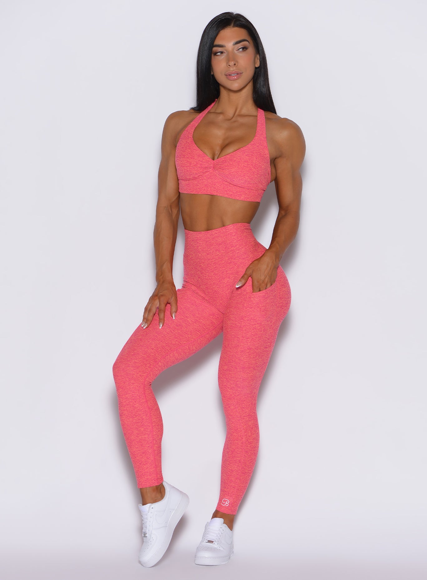 front profile view of a model wearing our V back leggings in Neon Tangerine Shock color along with a matching bra   