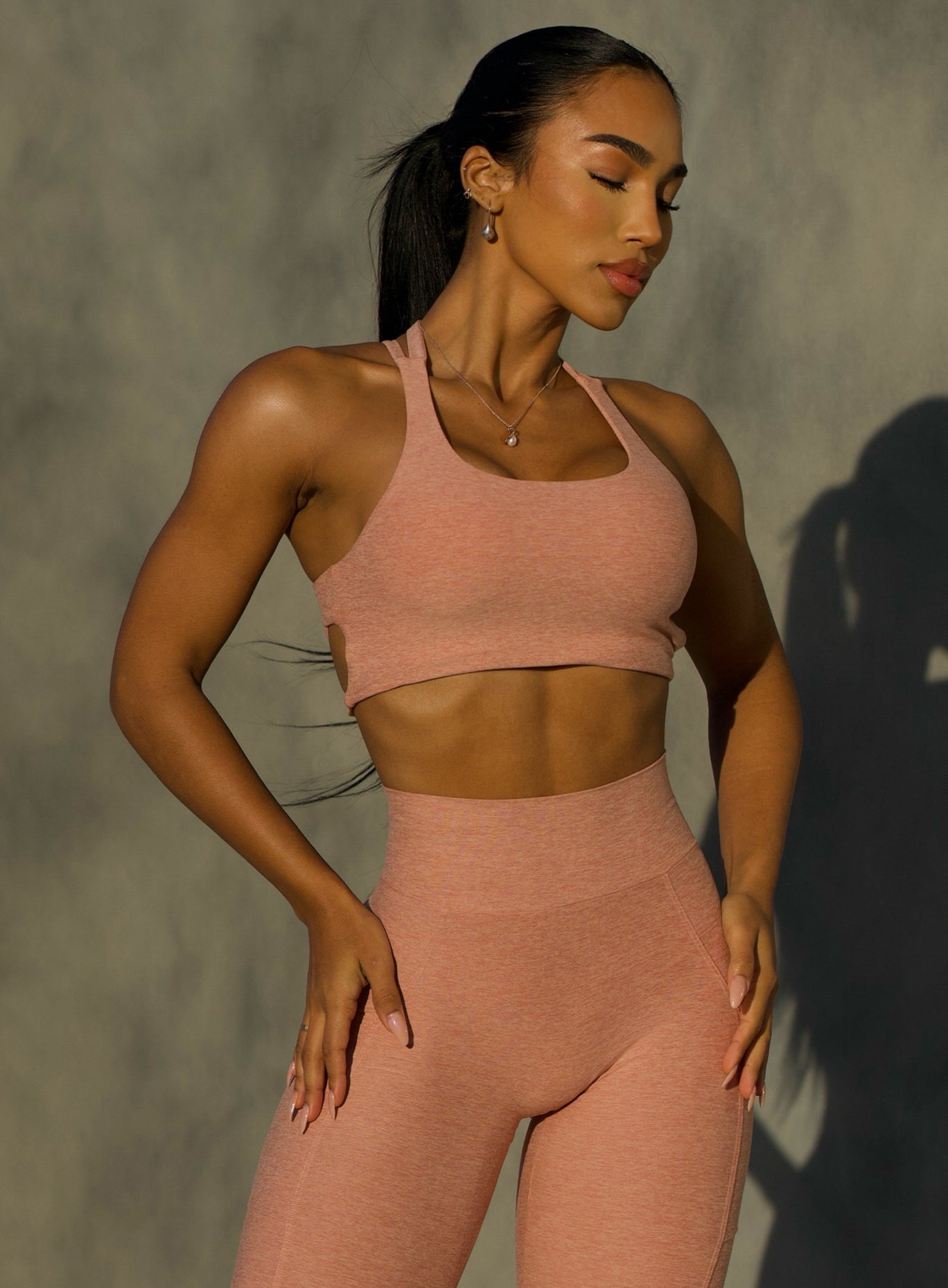 front  profile view of a model wearing our viral tank bra in nude sand color along with the matching leggings