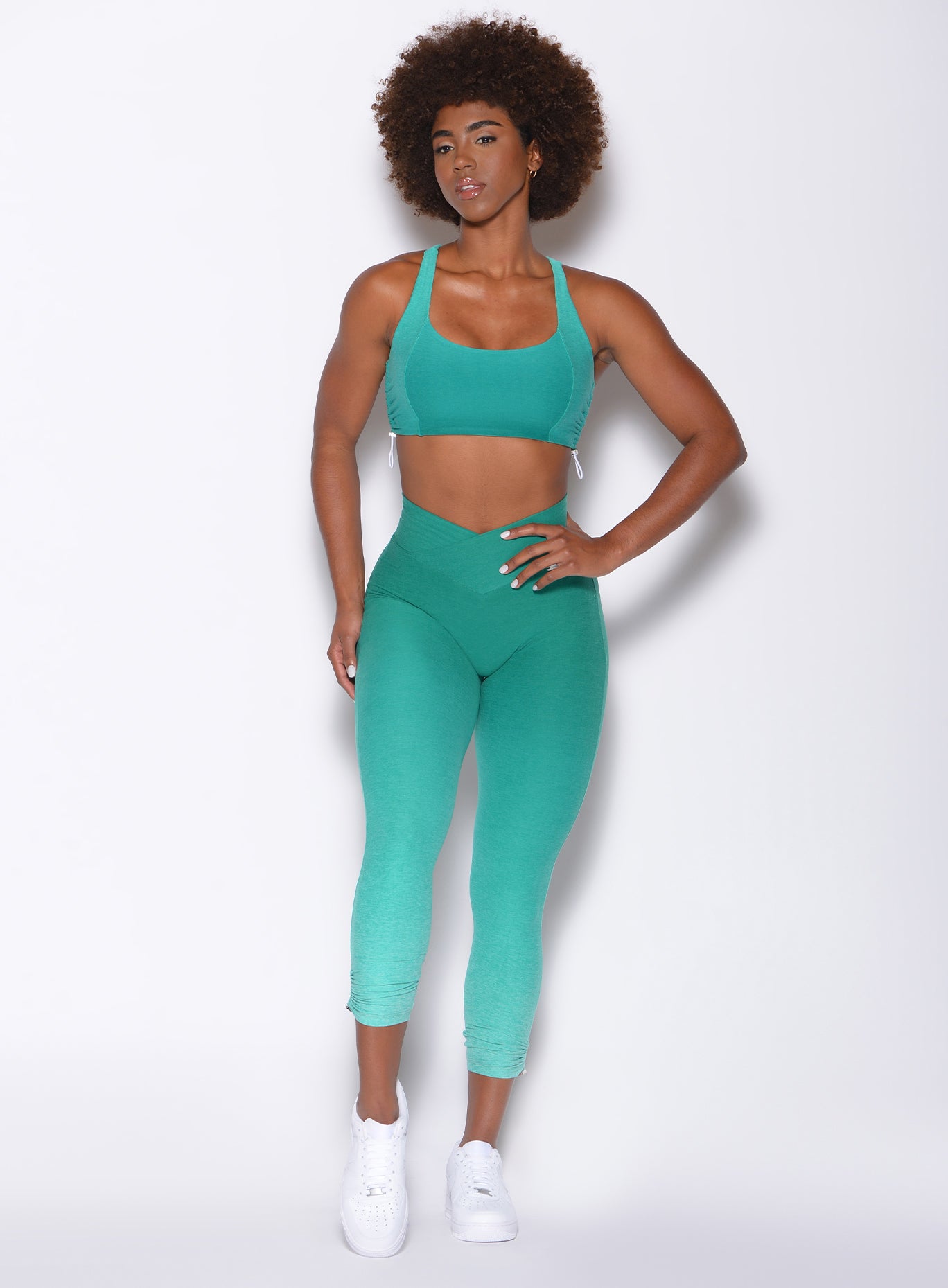 Front side profile view of a model wearing our toggle leggings in Ombre Ibiza Green and a matching sports bra