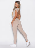 left side profile picture of a model facing towards the camera wearing our open back tee bodysuit in nude color