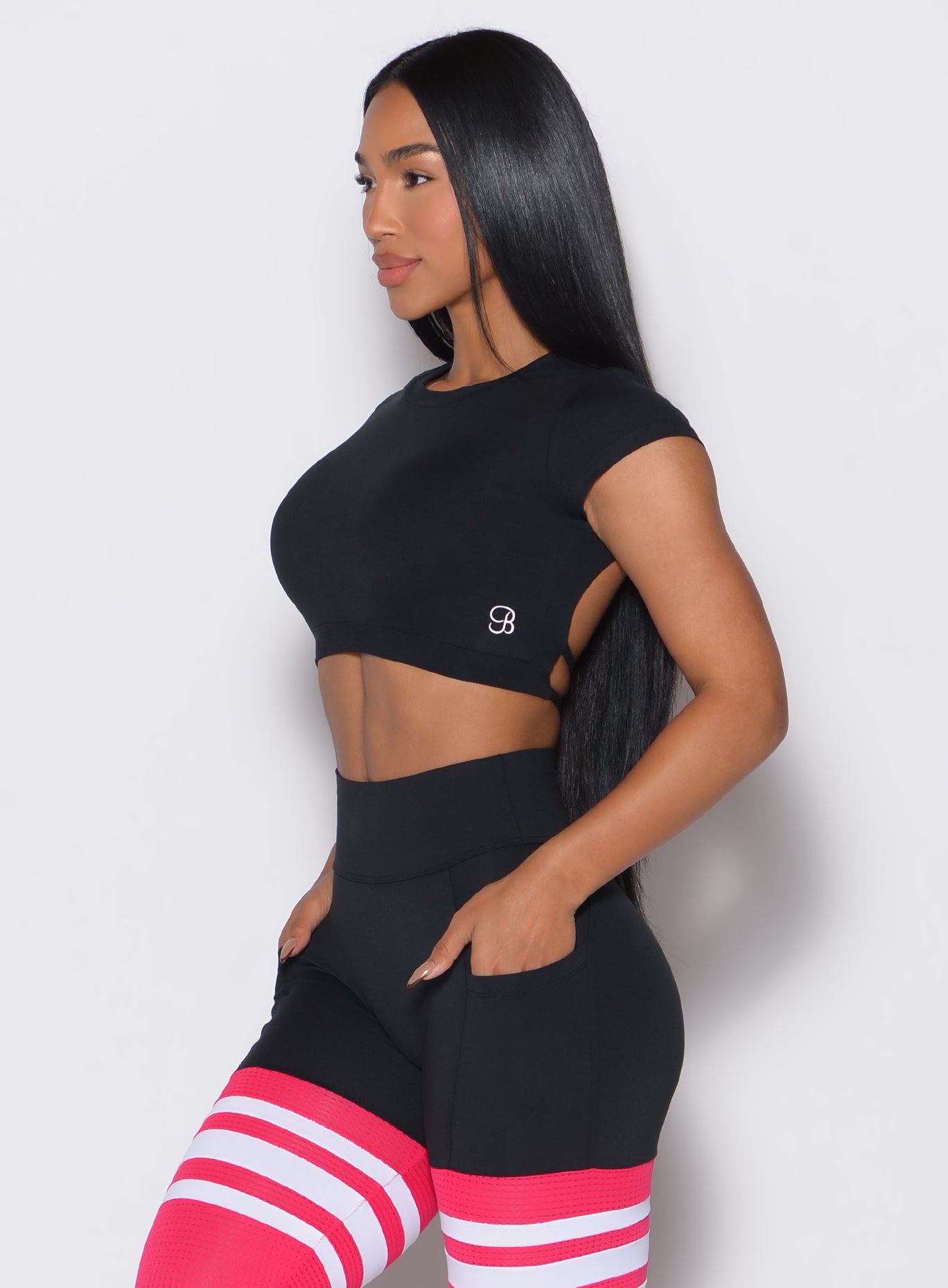left side  profile view of a model wearing our black open back tee along with a matching thigh high leggings