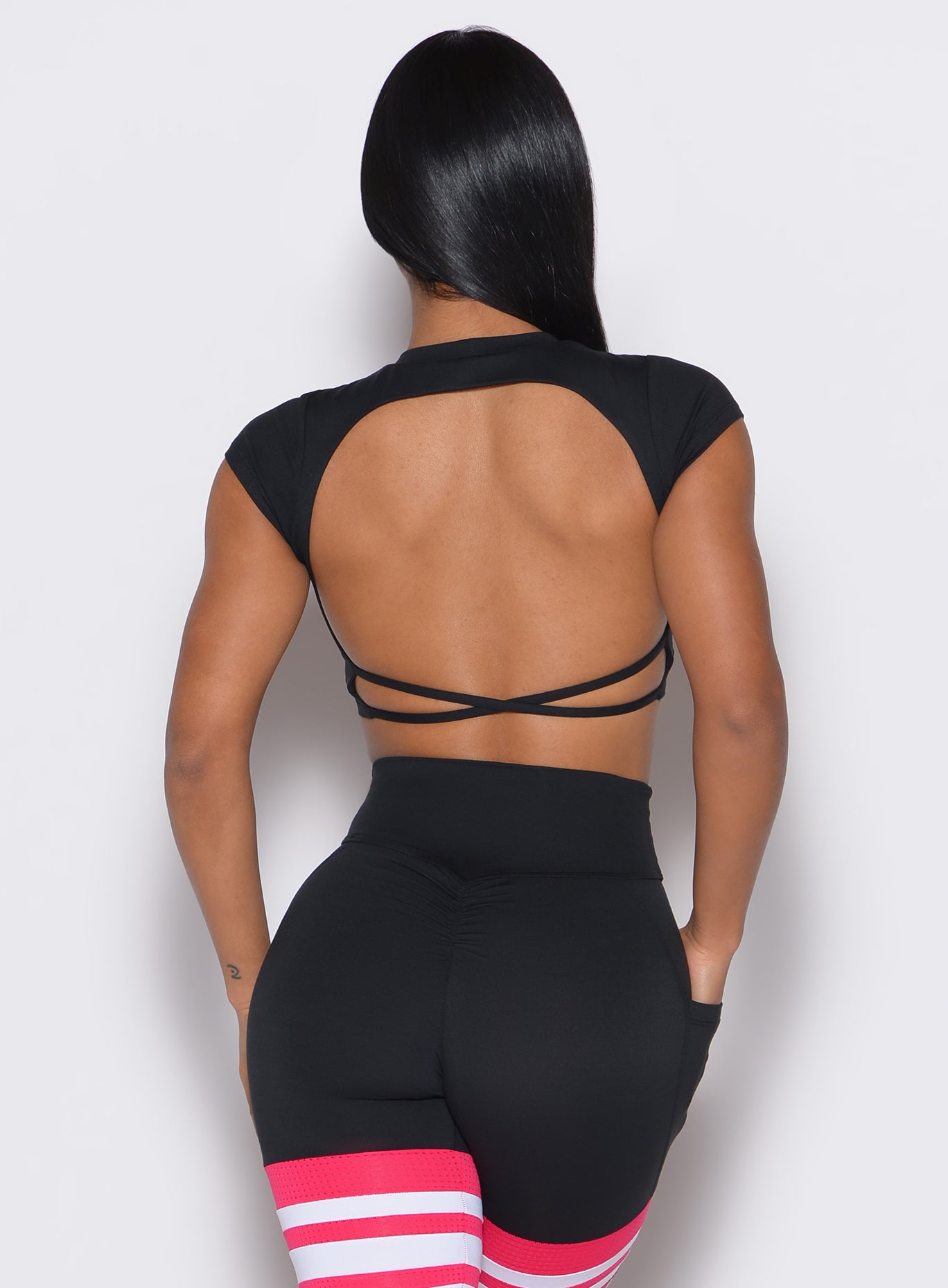 back profile view of a model wearing our black open back tee along with a matching thigh high leggings 