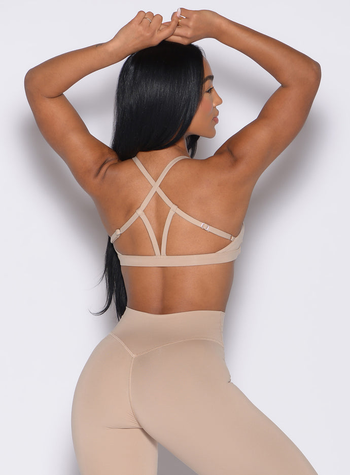 back profile view of a model with both hands resting on top of her head wearing the Passion Sports Bra in glacial beige color