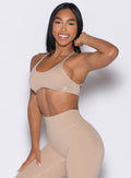front left side profile view of a model wearing the Passion Sports Bra in glacial beige color paired with the matching leggings 
