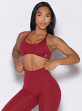 front profile view of a model holding the waistband of the leggings wearing the Passion Sports Bra in red velvet color