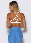 back profile view of a model facing to the left side wearing the Passion Sports Bra in white color