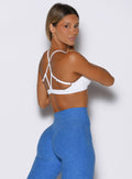 back right side profile view of a model looking over her shoulder wearing the Passion Sports Bra in white color