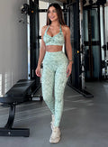 front view of a model at a gym wearing the Flexfit Leggings in Cool Matcha Leopard color paired with the matching bra