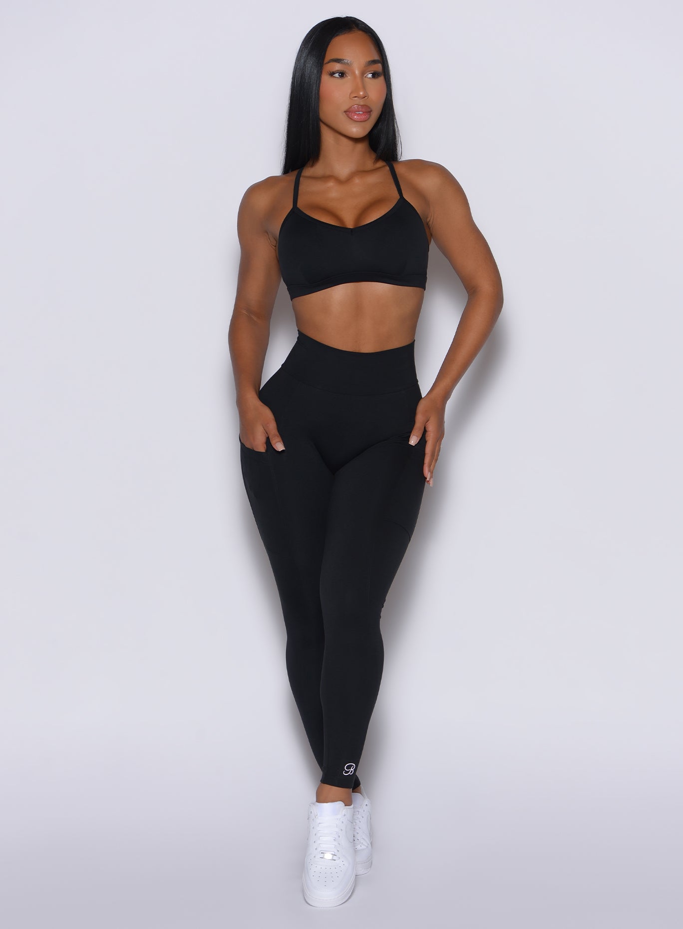 front profile view of a model wearing our black peach pocket leggings along with a matching bra 