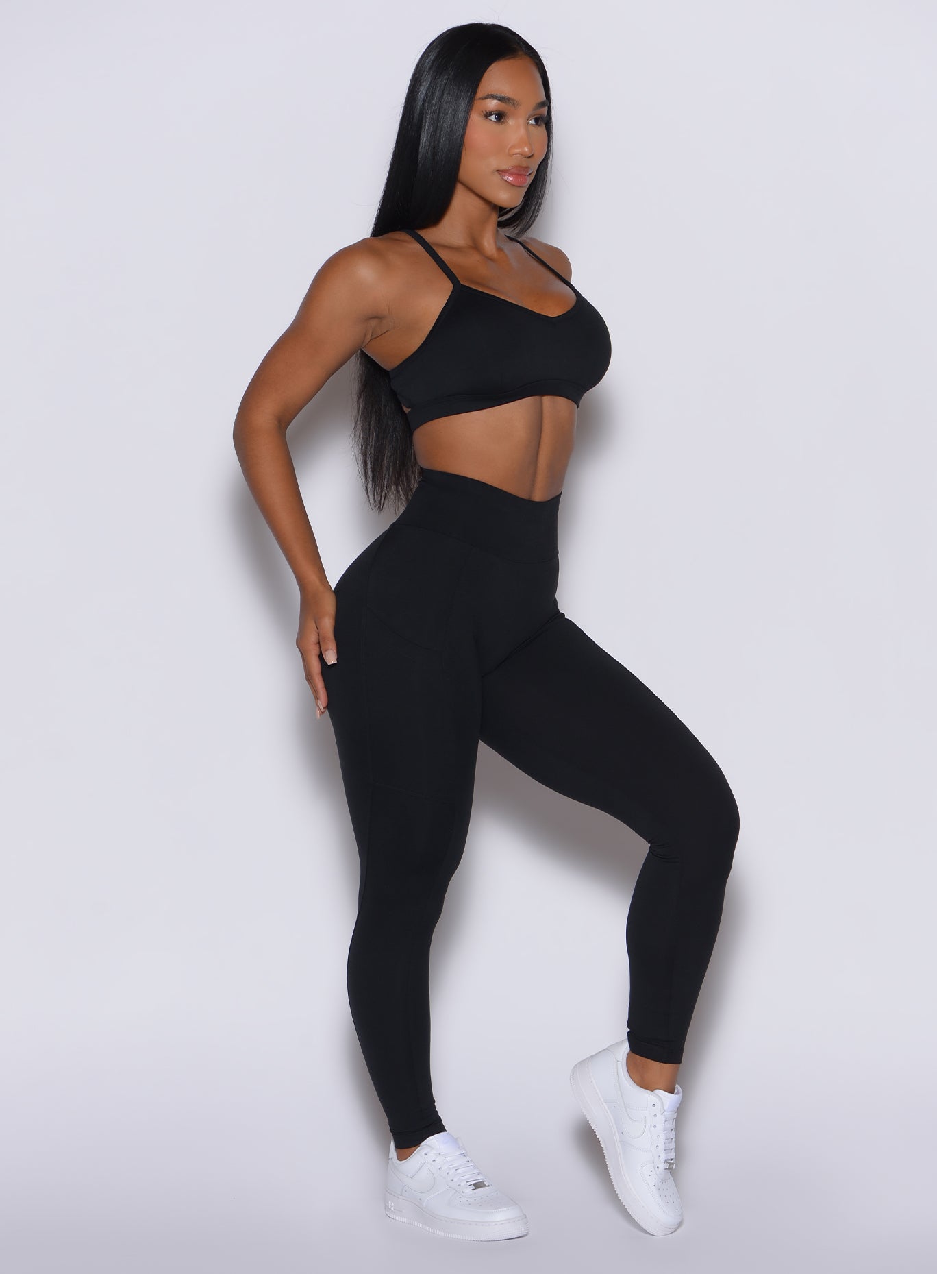 right side profile view of a model wearing our black peach pocket leggings along with a matching sports bra