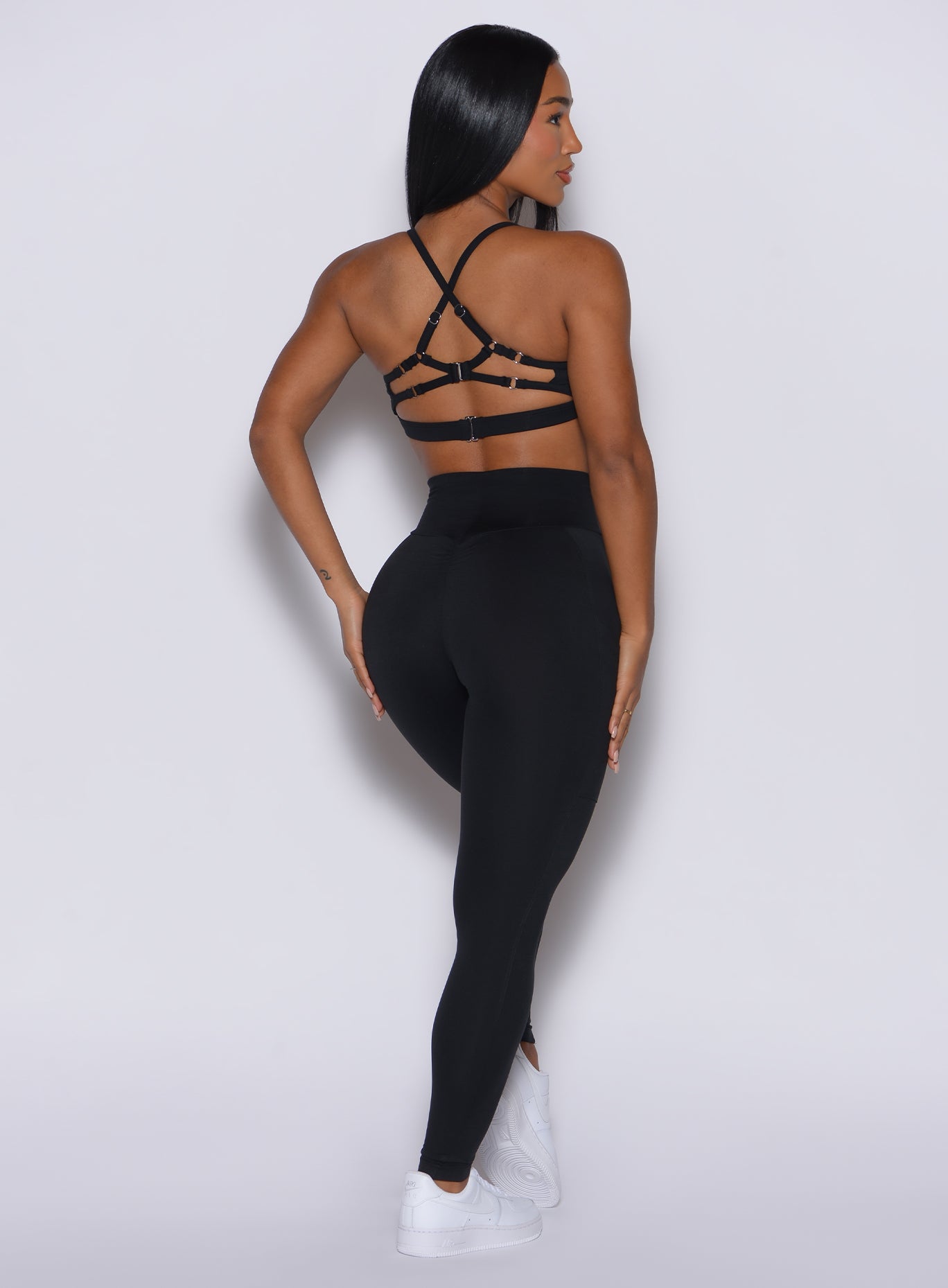 Back profile view of a model wearing our black peach pocket leggings along with a matching sports bra
