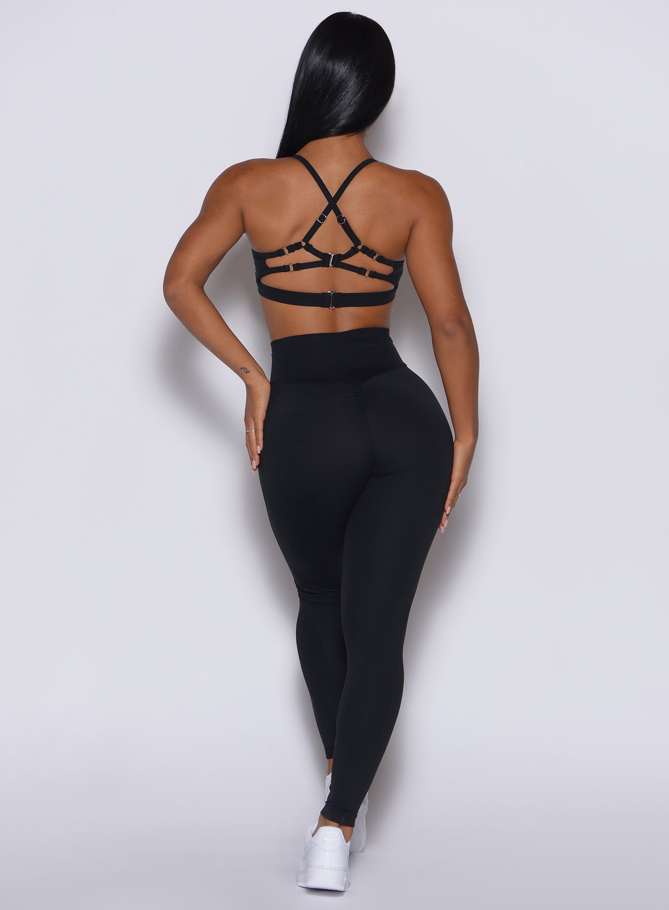 Back profile view of a model wearing our black peach pocket leggings along with a matching bra