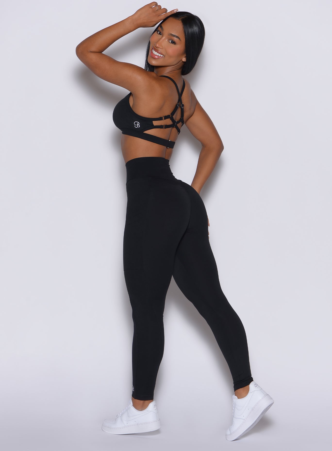 Left side profile view of a model in our black peach pocket leggings along with a matching bra